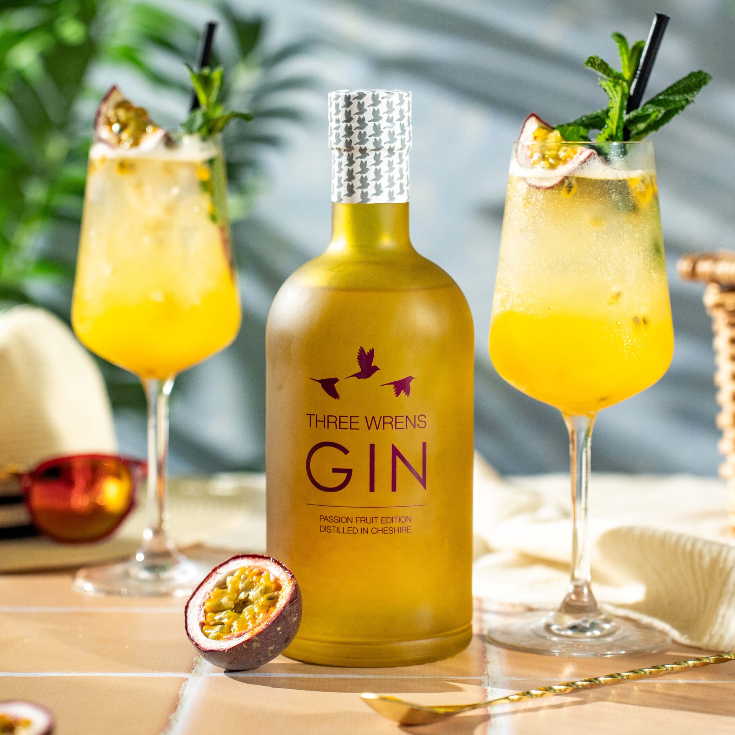 passion fruit flavour gin 70cl bottle with poco grande glasses and passion fruit slices sunshine terracotta tiles