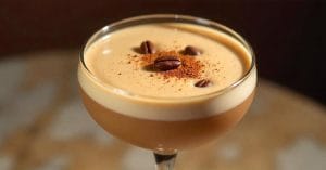 Creamy espresso martini in a coupe glass, topped with coffee beans and a dusting of cocoa powder.